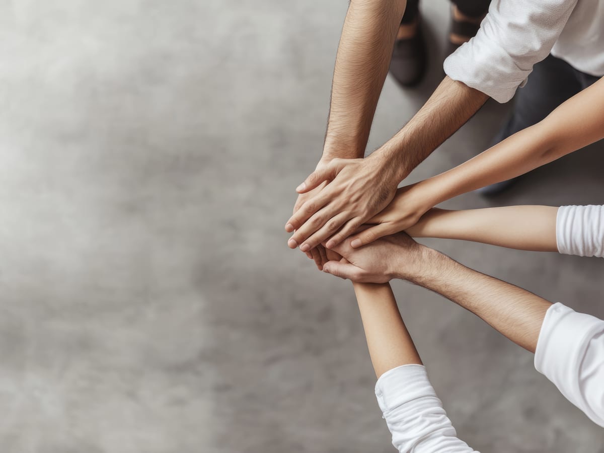 Mani di più persone unite al centro, a simboleggiare il lavoro condiviso della rete